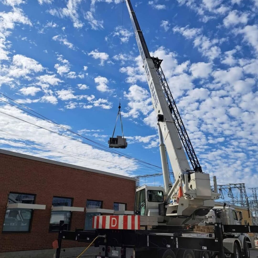 A crane lifting a rooftop unit onto a brick building, photographed by Dundas Mechanical (Instagram, January 2025)